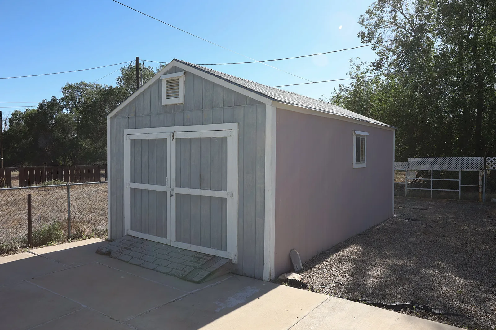 Detached storage shed with dual barn doors, a side window, and a roof vent