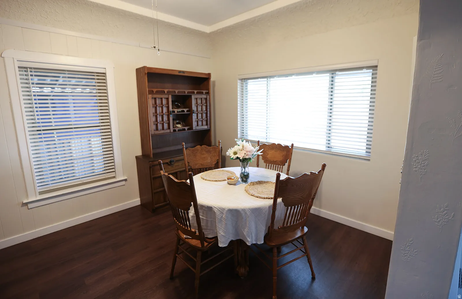 Dining area featuring dark wood-finish LVP flooring, white baseboards, and neutral wall tones