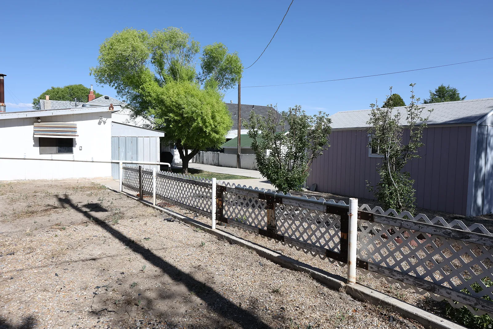 Lattice-style perimeter fencing with a gravel yard