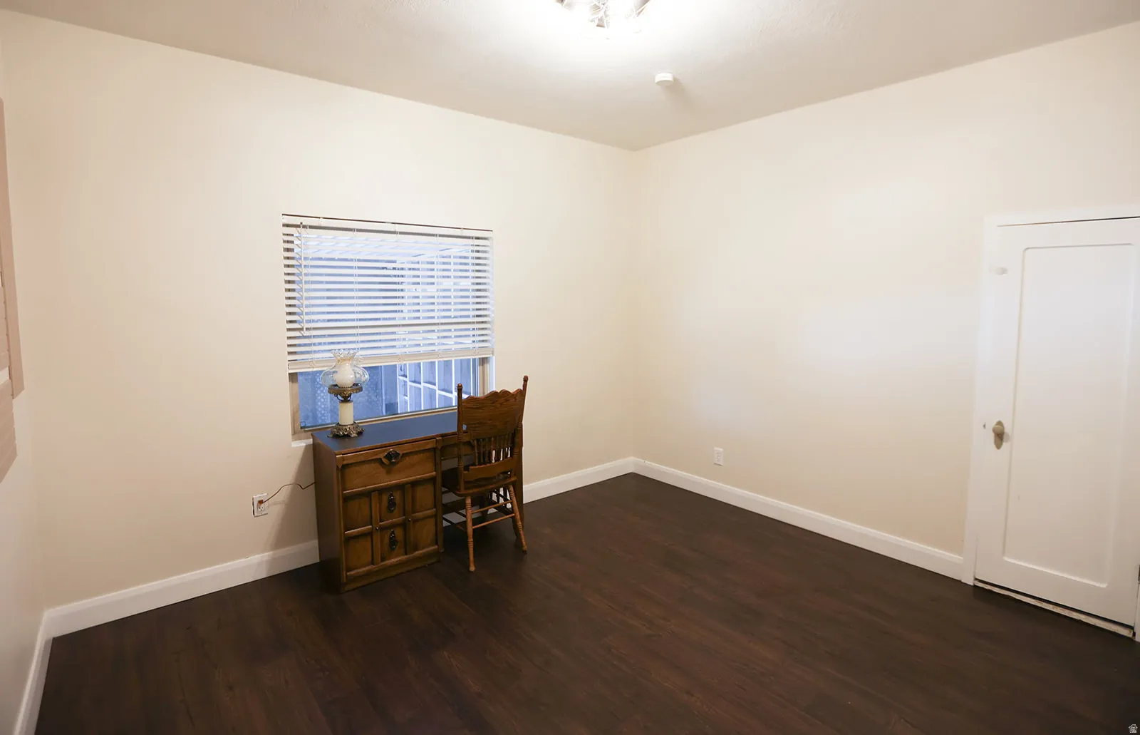 Room featuring dark wood-finish LVP flooring, light neutral-toned walls, and white baseboards