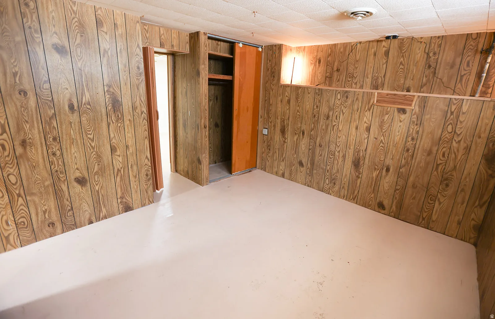 Interior space featuring wood paneling, a drop ceiling, and light-colored flooring