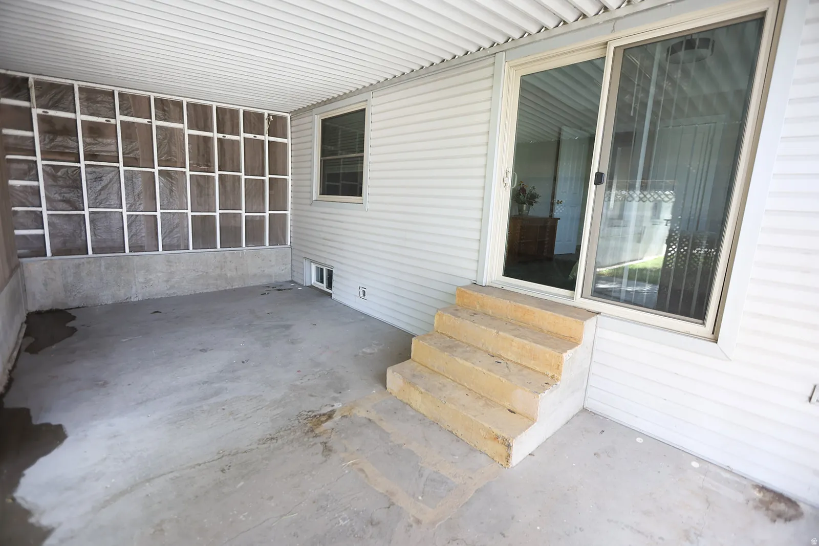 Covered patio with a concrete floor, vinyl siding, and a translucent panel wall