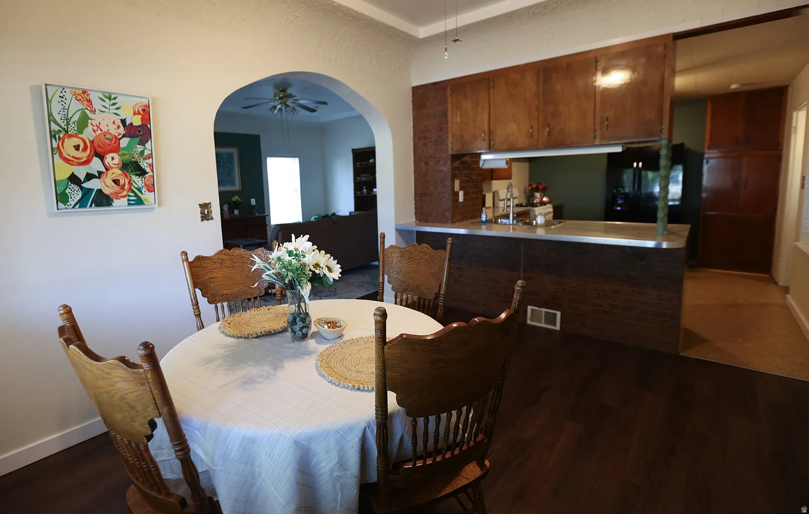 Dining area with dark wood-finish LVP flooring and an arched doorway