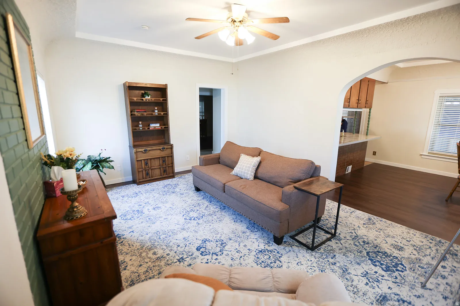 Spacious living area featuring light-toned walls, crown molding, and a ceiling fan with integrated lighting