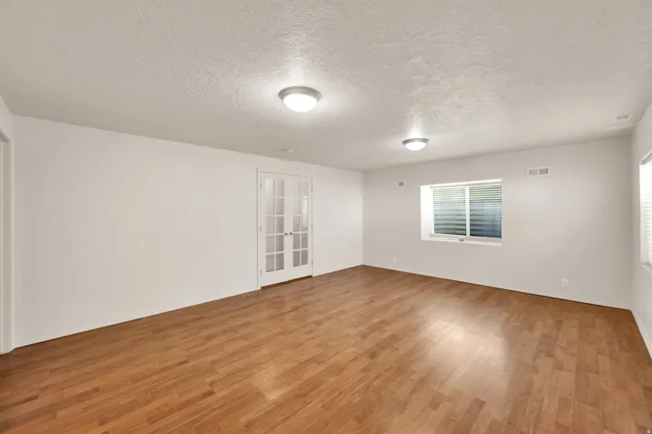 Spacious room featuring wood-finish flooring, white walls, and recessed lighting