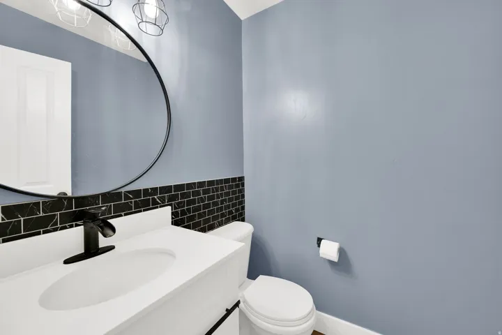 Bathroom vanity with a white countertop and integrated sink, matte black faucet, and black subway tile backsplash