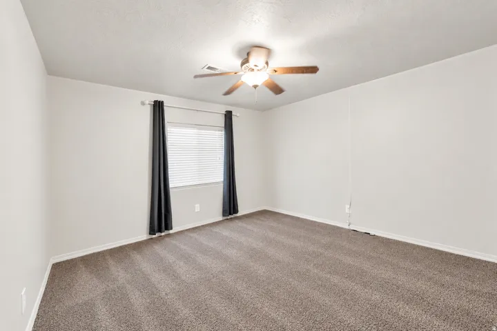 Neutral wall paint, ceiling fan, carpet flooring, and window with blinds