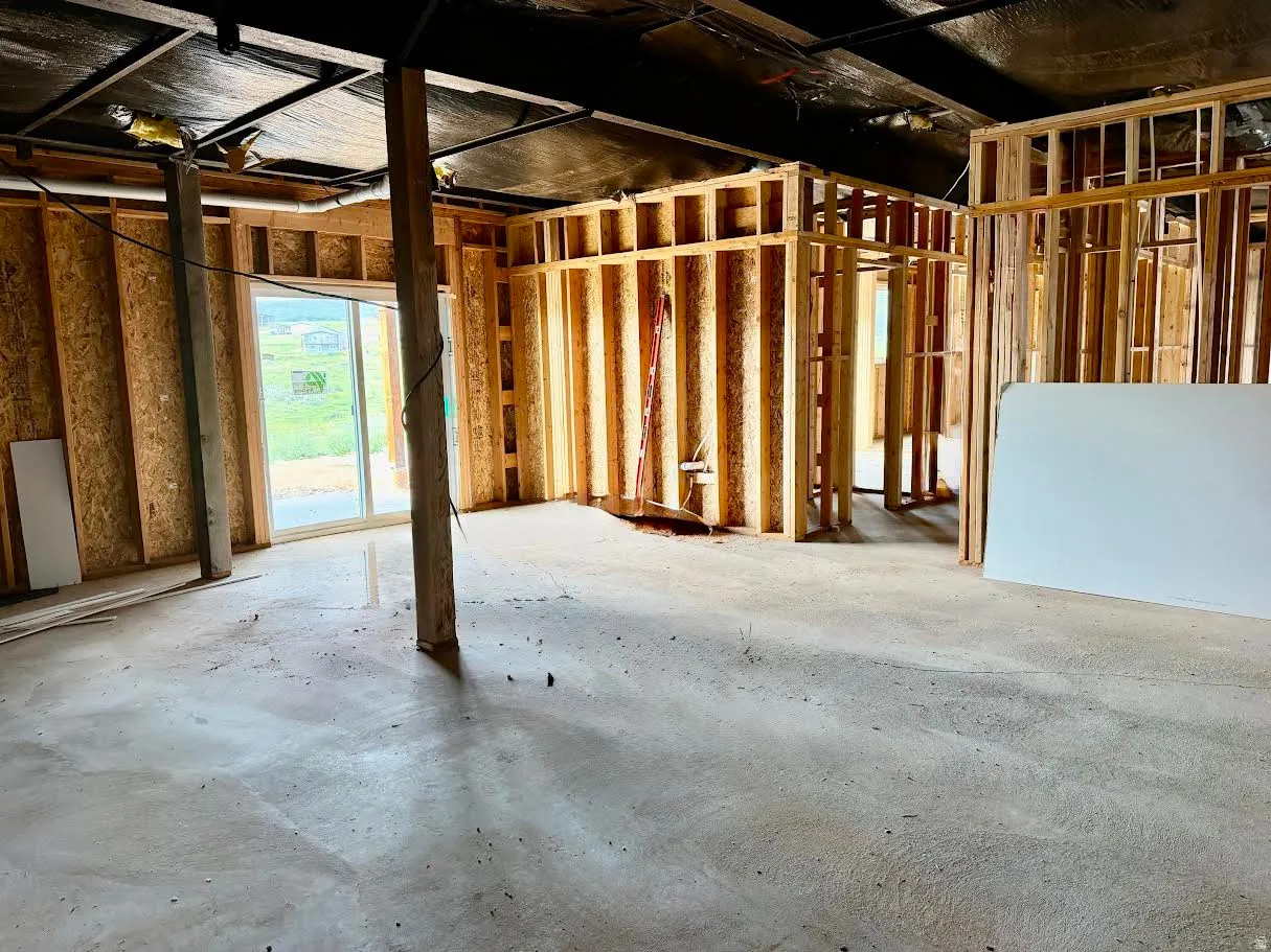 Unfinished lower level featuring wood framing, exposed concrete flooring, and a sliding glass door
