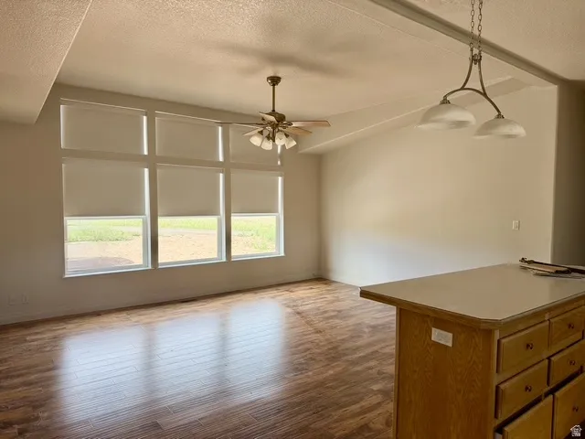 Open-concept living area featuring wood-finish flooring, a vaulted ceiling, and a multi-pane window array