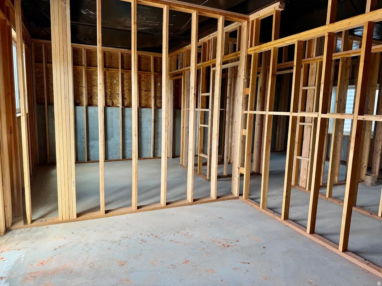 Unfinished interior space featuring wood framing, concrete flooring, and exposed insulation