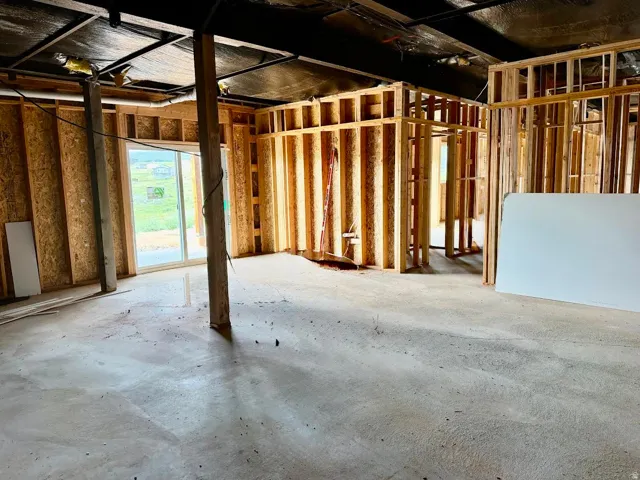 Unfinished lower level featuring wood framing, exposed concrete flooring, and a sliding glass door