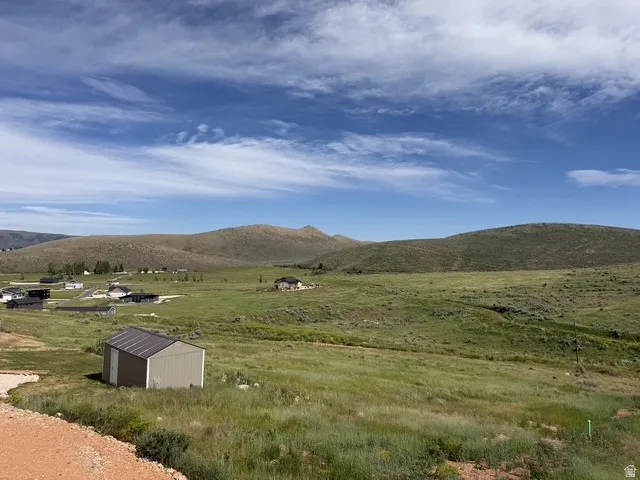 Expansive rural landscape featuring rolling hills and distant residential structures