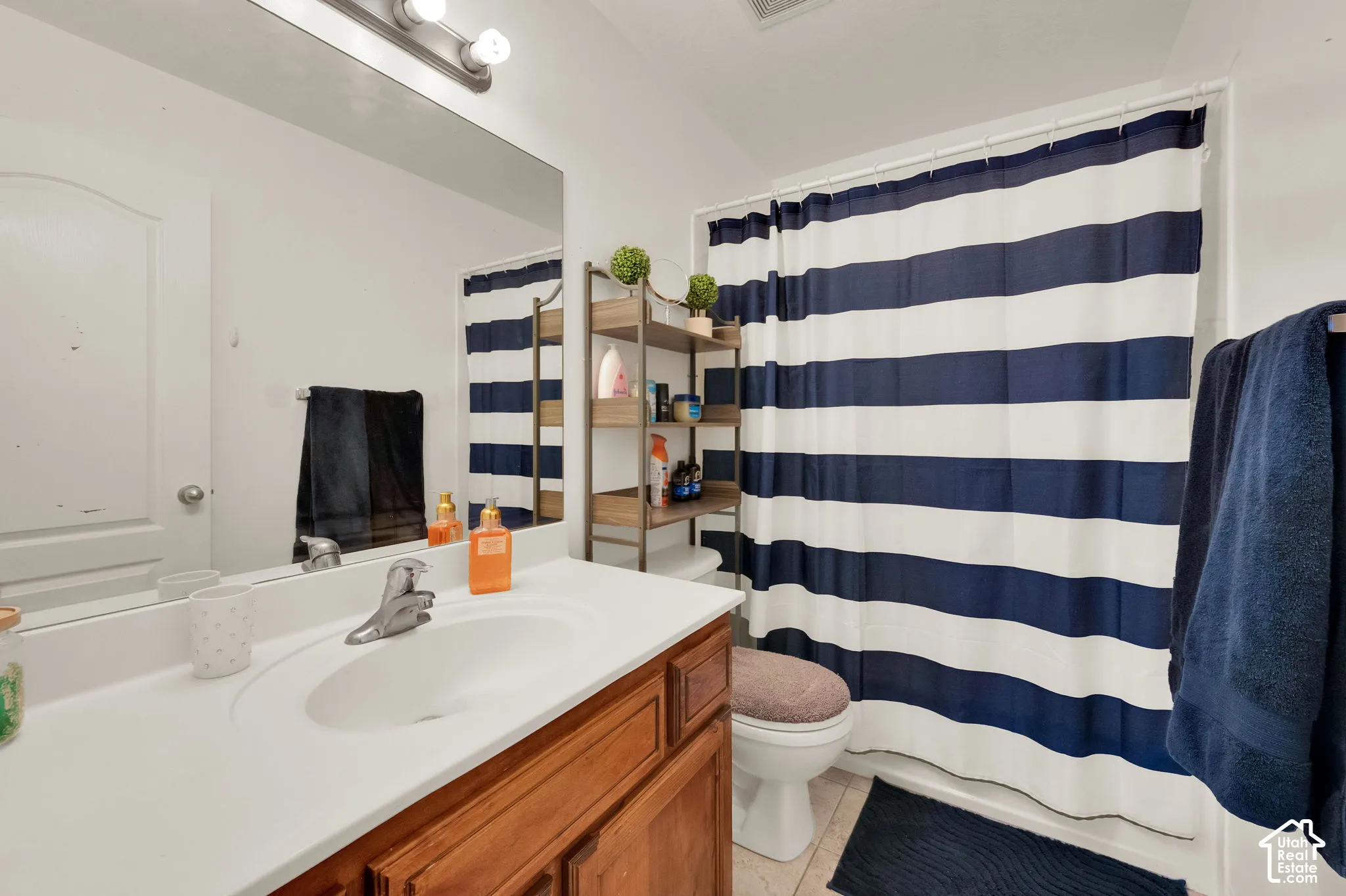Full bathroom featuring a wood-finish vanity with an integrated sink, polished chrome faucet, and a large wall-mounted mirror