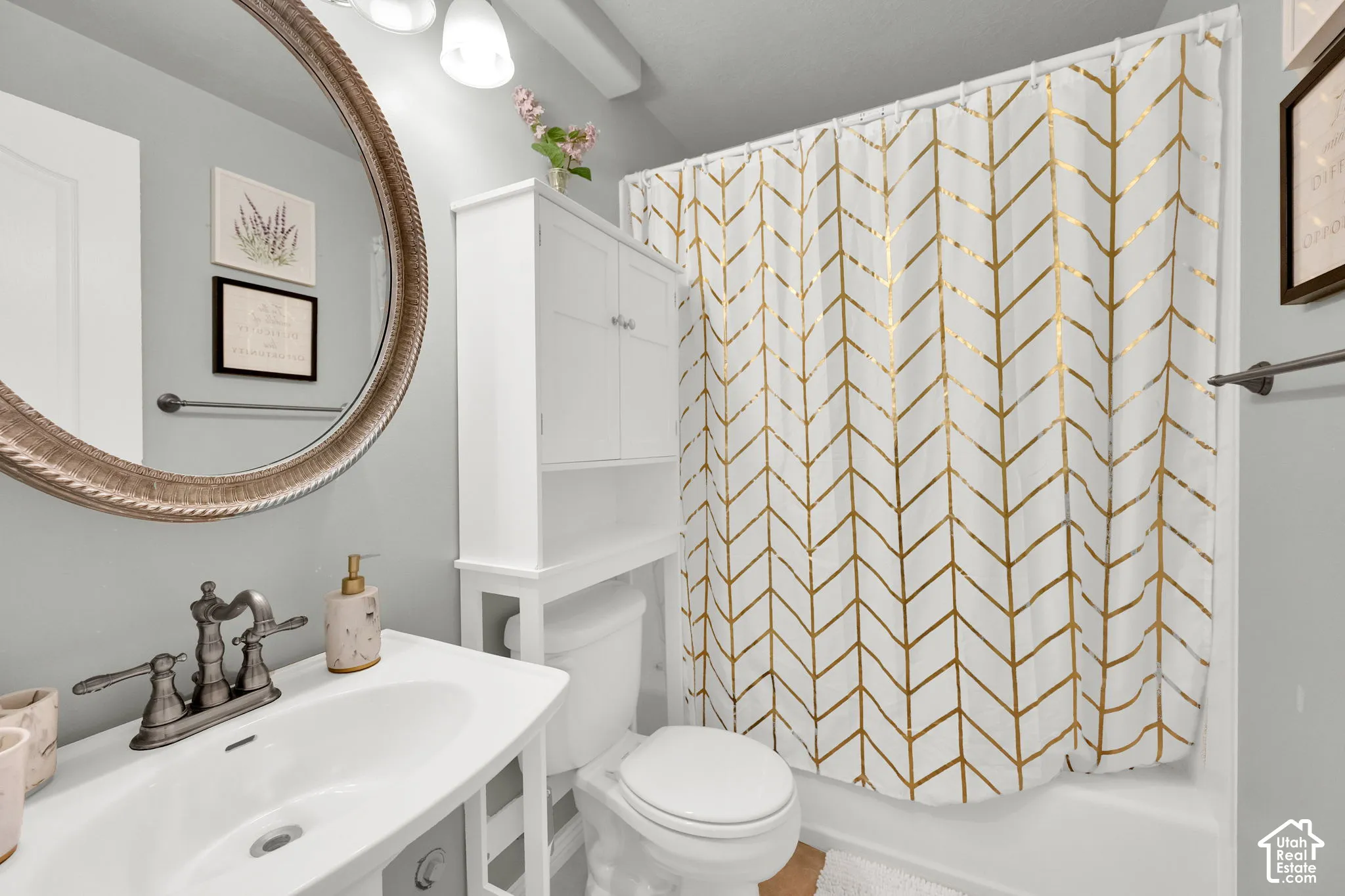 Bathroom featuring a white vanity with integrated sink, bronze-finish faucet, and a large round mirror