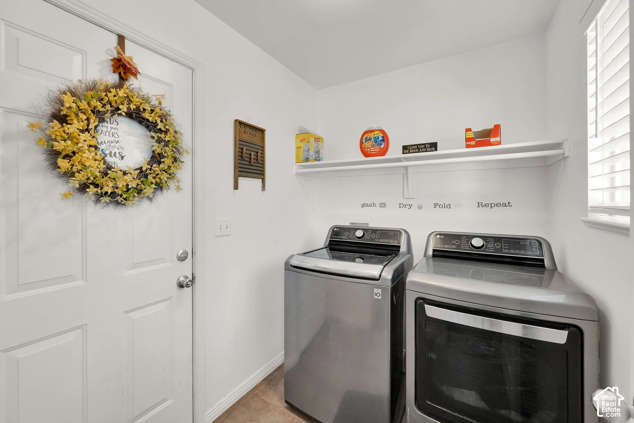 Laundry area featuring a built-in wall shelf, a window with blinds, and durable tile flooring