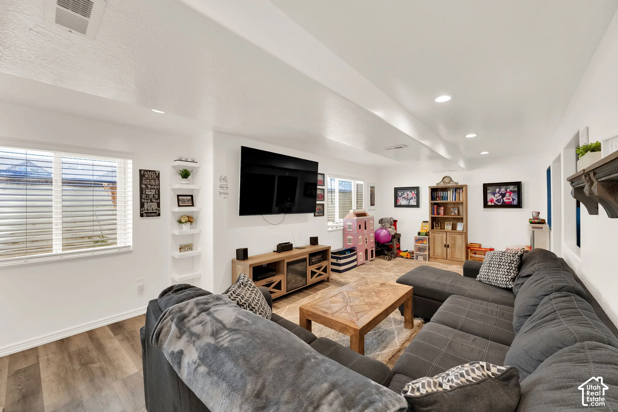 Spacious lower-level living area featuring recessed lighting, a corner shelving unit, and multiple windows