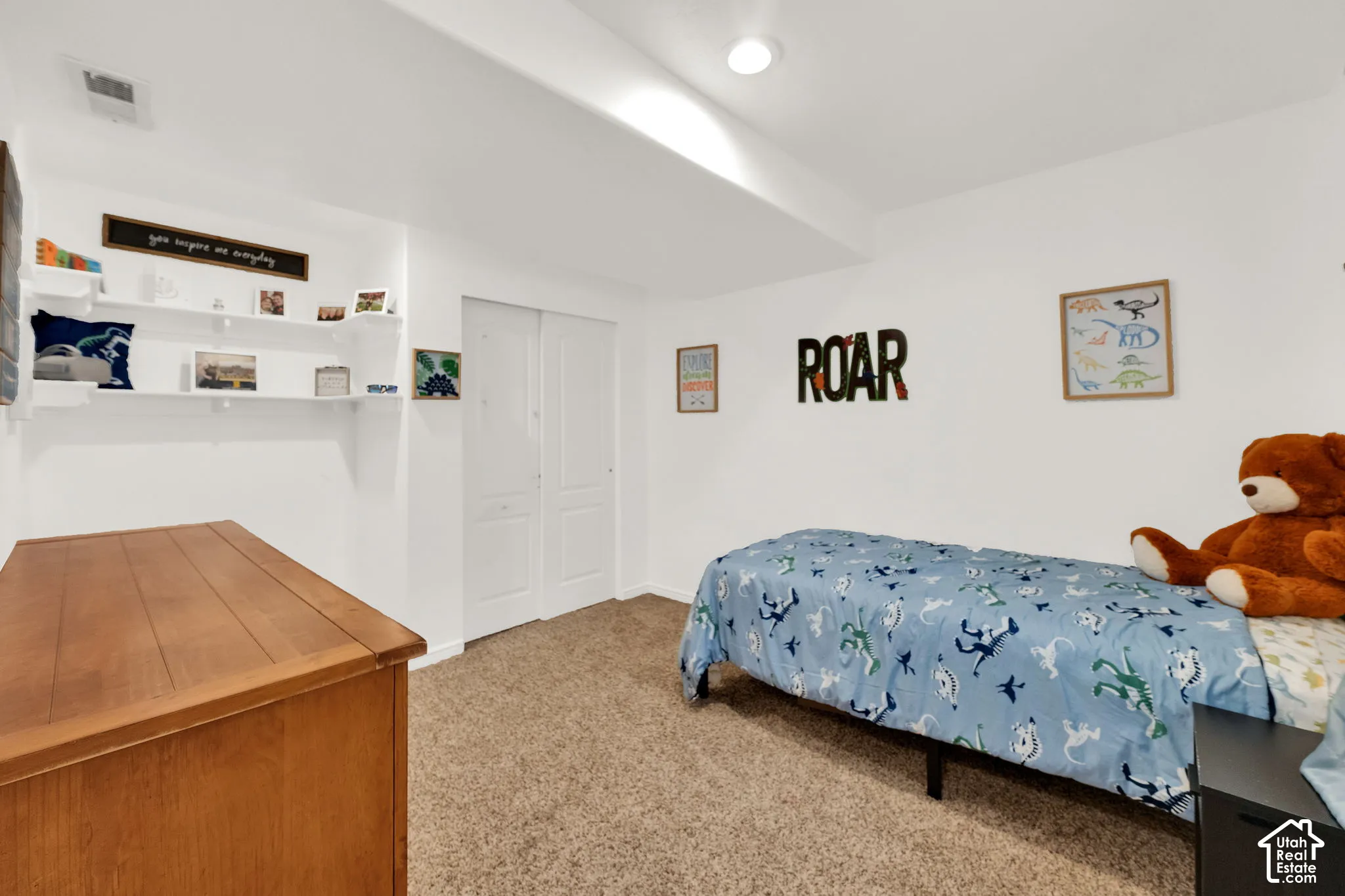 Bright white walls featuring built-in shelving, soft carpet flooring, and a flush-mount ceiling light