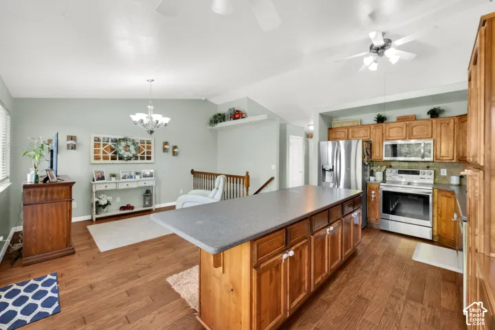 Spacious kitchen island with a dark countertop, wood-finish flooring, recessed lighting, and stainless steel appliances