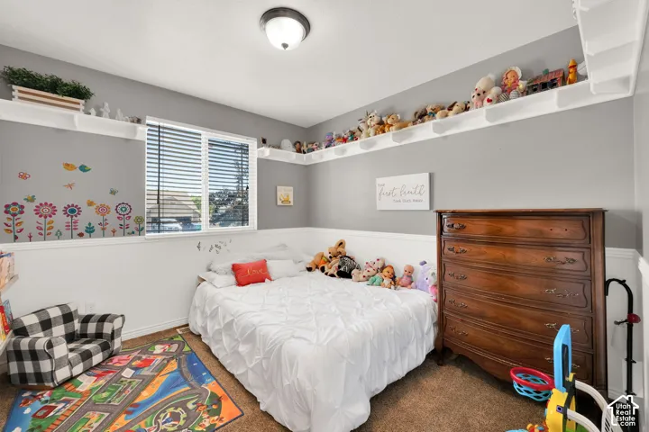 Carpeted room featuring a window with blinds, white shelving around the perimeter, a white chair rail, and a semi-flush mount ceiling light fixture