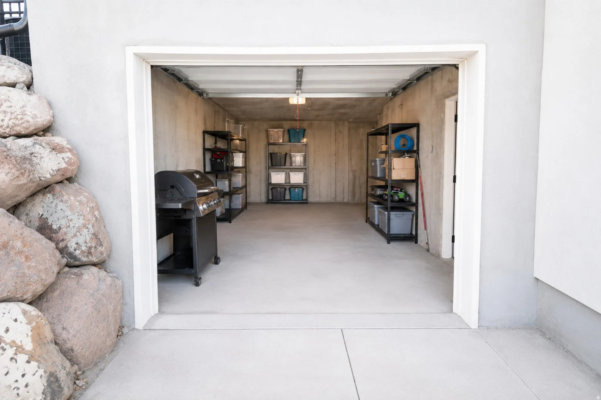 Spacious interior garage with concrete flooring, exposed ceiling, and integrated storage shelving