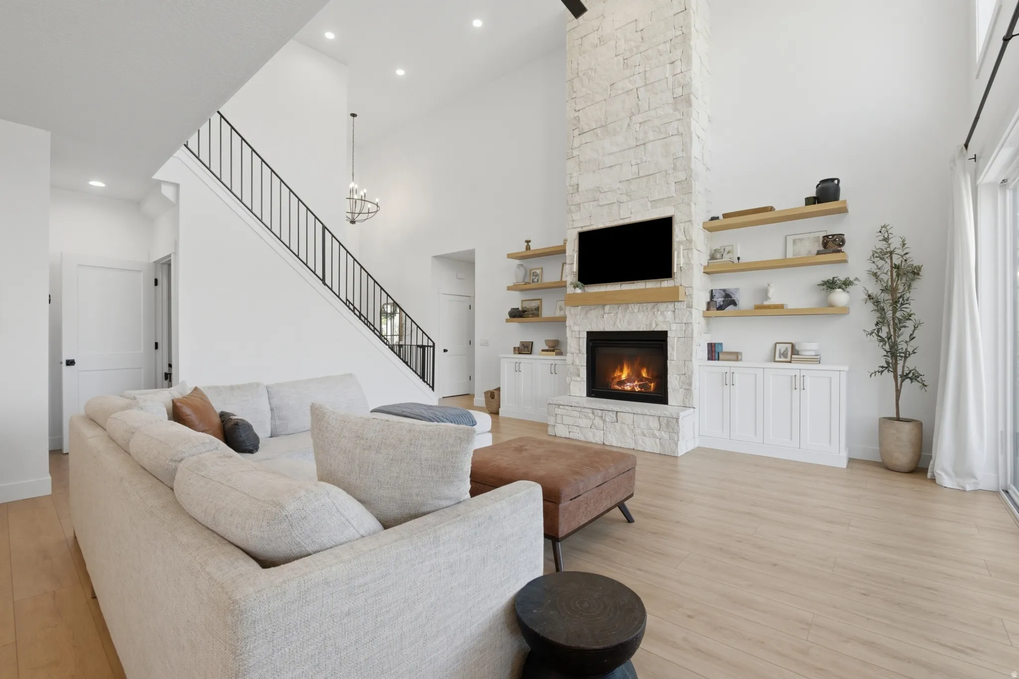 Living space featuring a soaring vaulted ceiling, stone-clad fireplace, and integrated wood-finish shelving