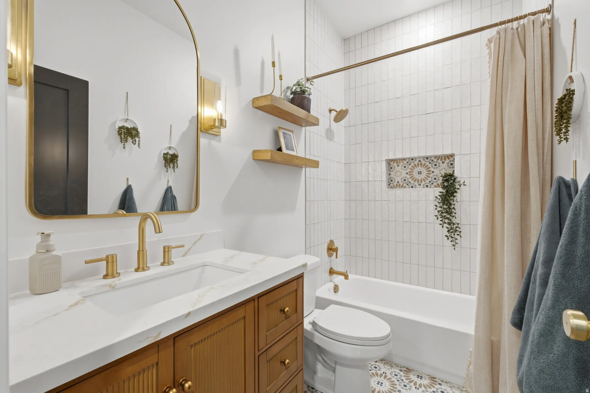 Bathroom featuring a white bathtub with subway tile surround, patterned floor tiling, and a recessed tiled niche