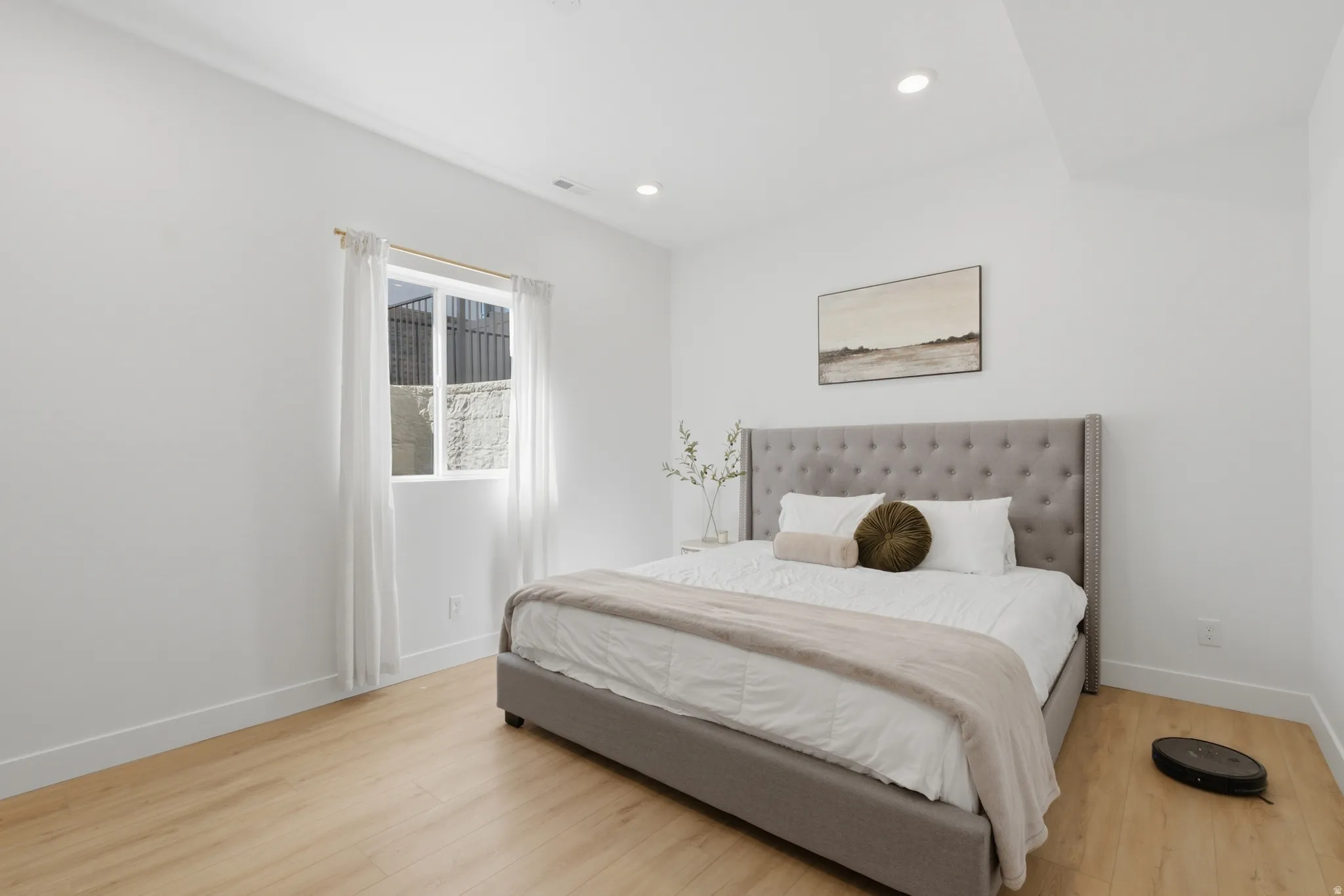 Spacious room featuring light wood-finish flooring, recessed lighting, and a large window with white trim