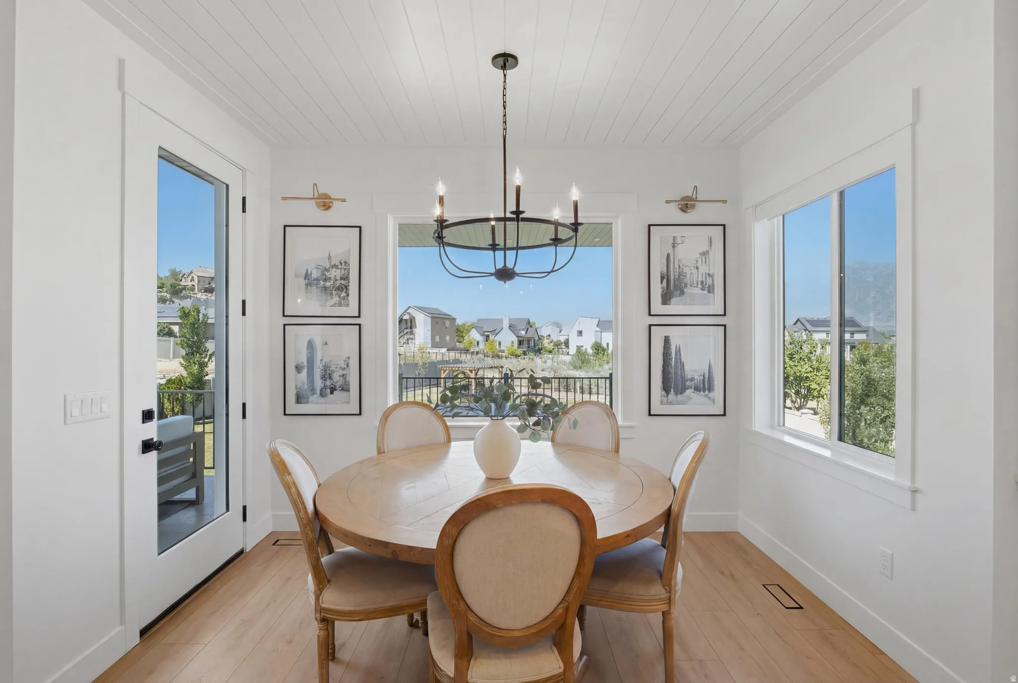 Bright dining area featuring a full-light exterior door, a large picture window, and wood-finish flooring