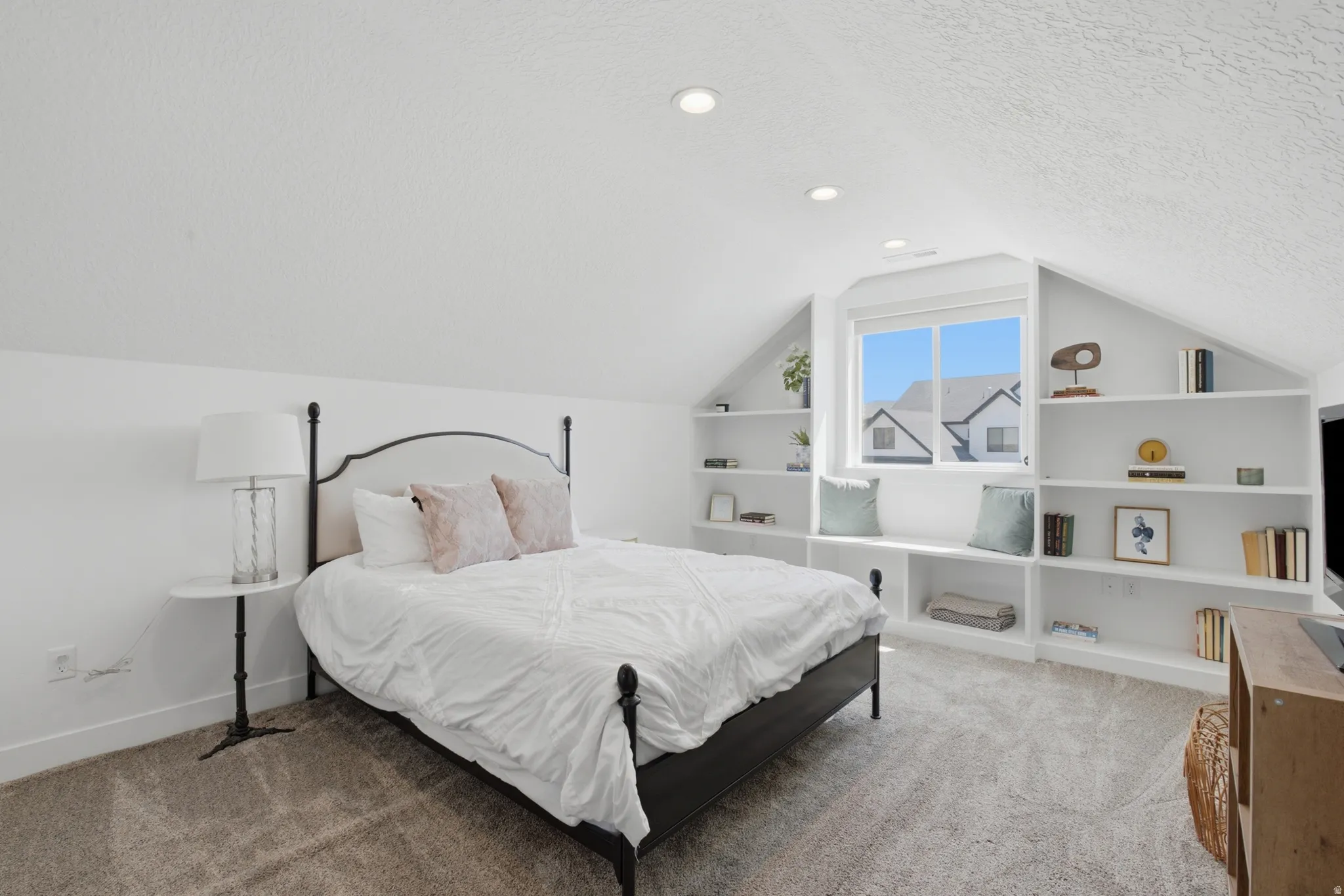 Attic room featuring recessed lighting, a window with a built-in bench seat, extensive integrated shelving, and sloped ceilings