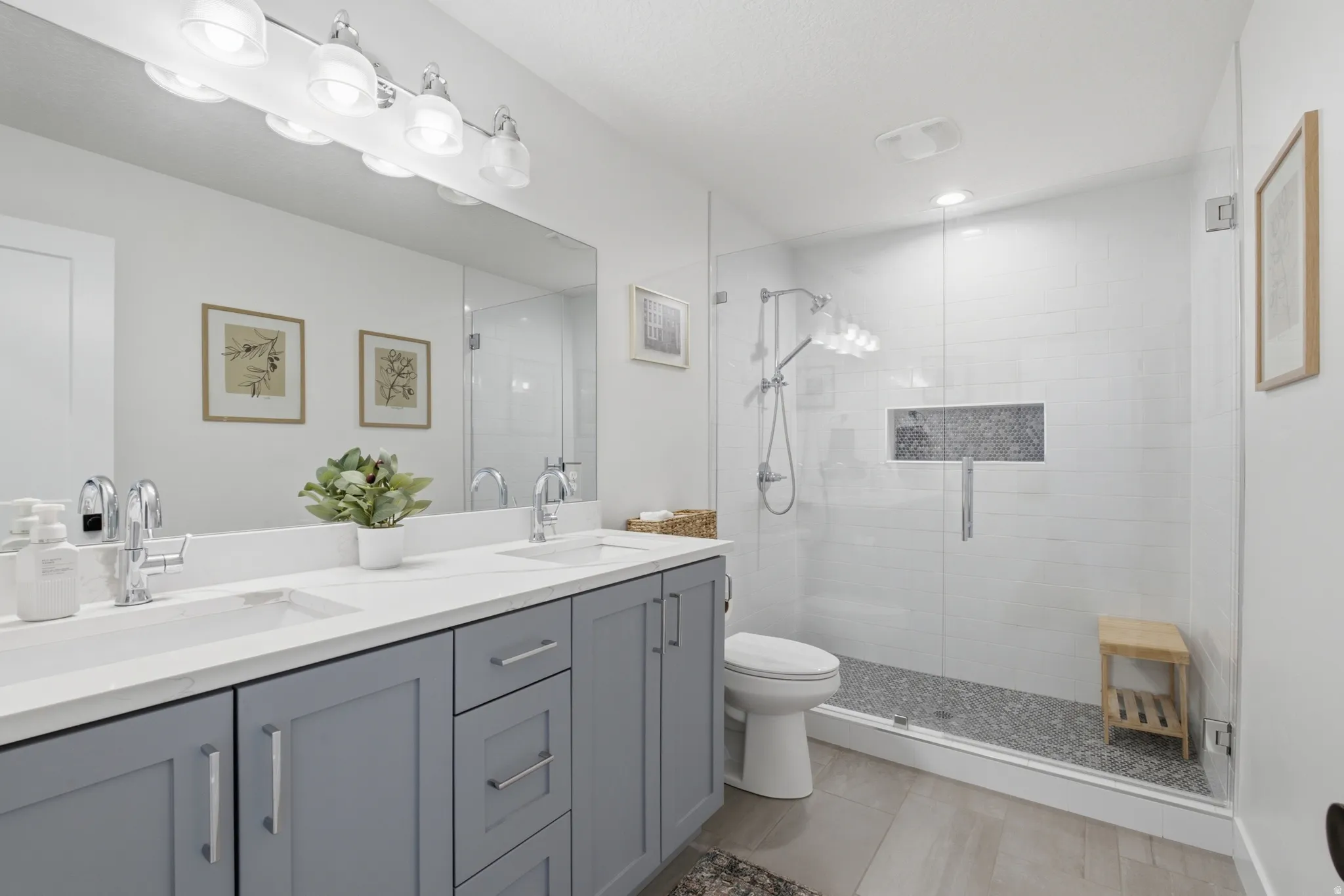 Bathroom featuring a dual vanity with light grey cabinetry and a spacious glass-enclosed shower