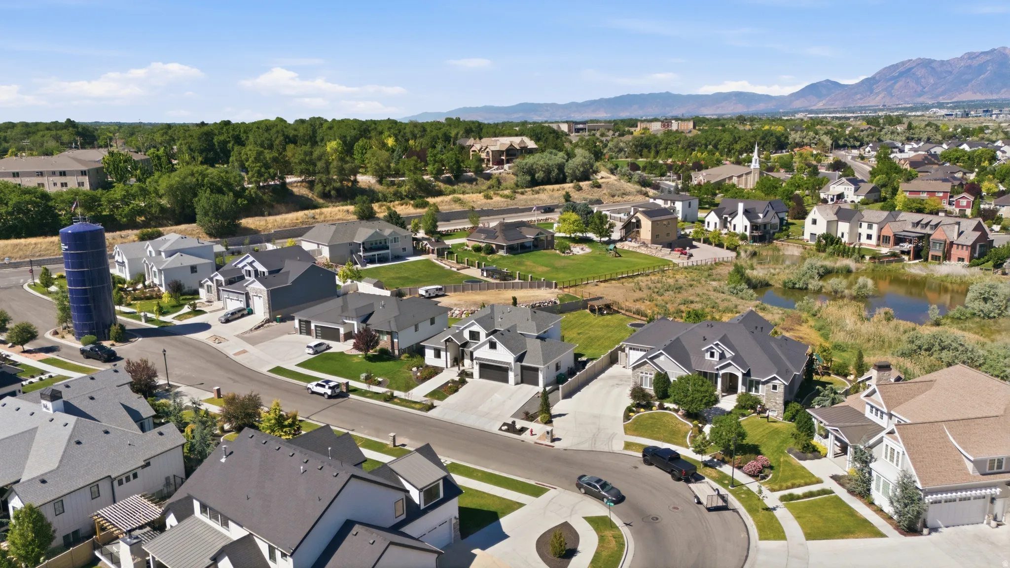 Aerial perspective showcasing a residential neighborhood with diverse architectural styles, mature landscaping, and mountain backdrops
