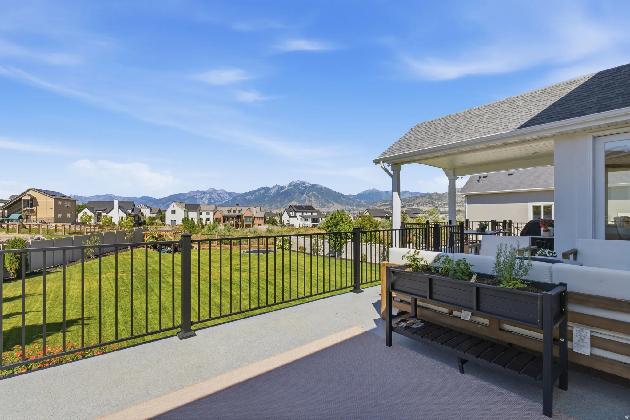 Spacious outdoor deck featuring a covered patio, black metal railing, and expansive mountain scenery