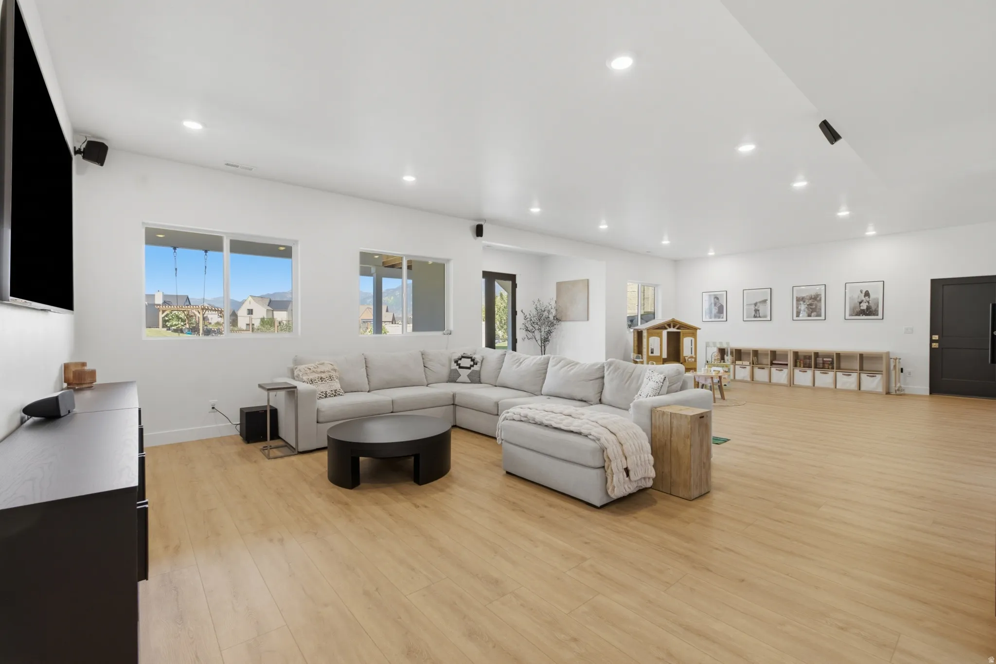 Expansive open-plan living area featuring wood-finish flooring and recessed lighting throughout