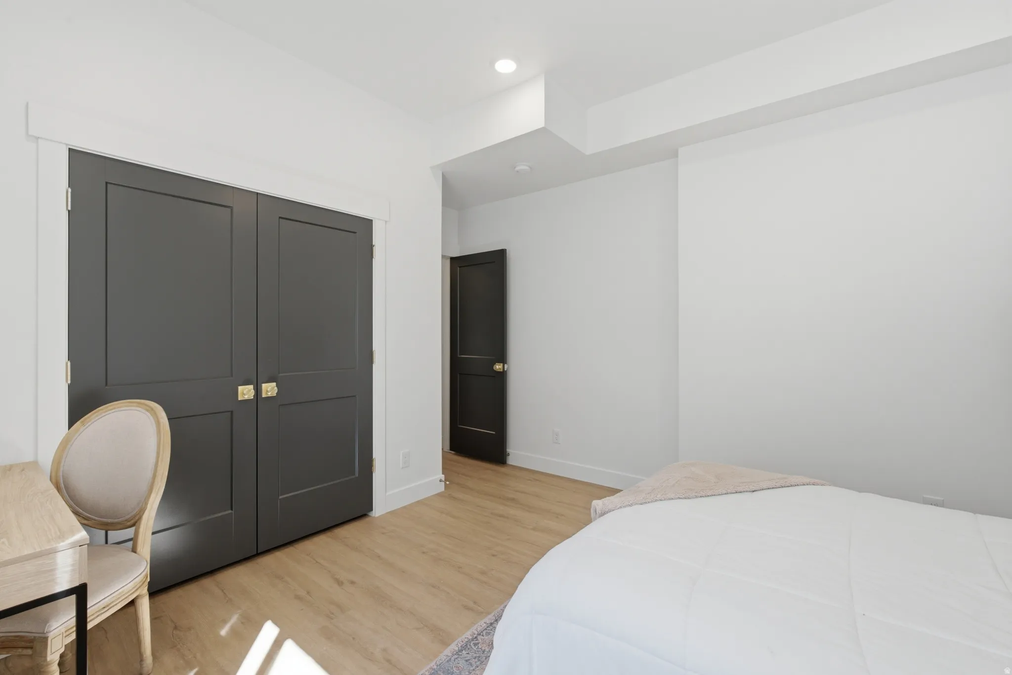 Interior room featuring light wood-finish flooring, white walls, and bright recessed lighting