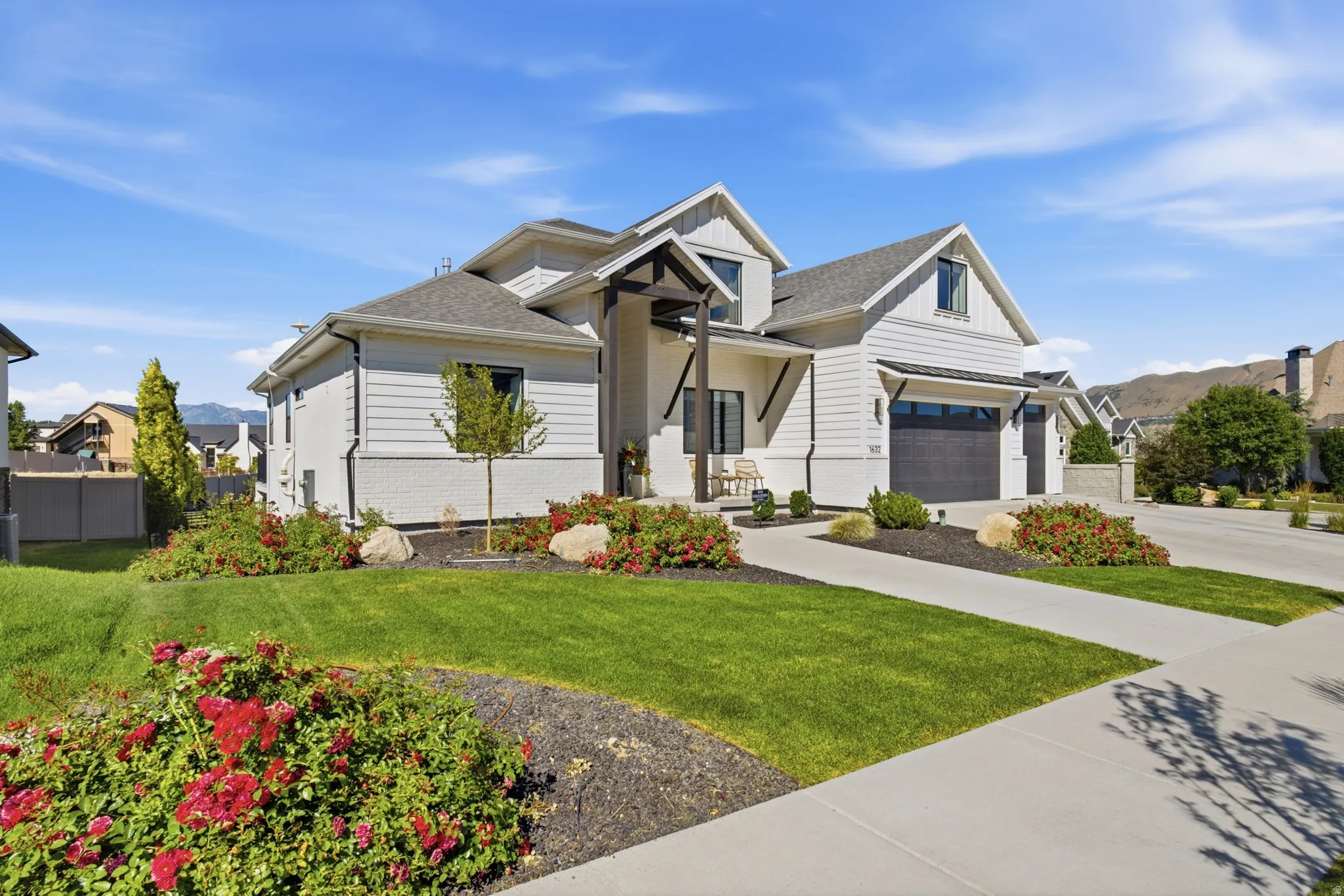 Modern farmhouse exterior with white siding and brick accents, featuring a dark wood pergola entry