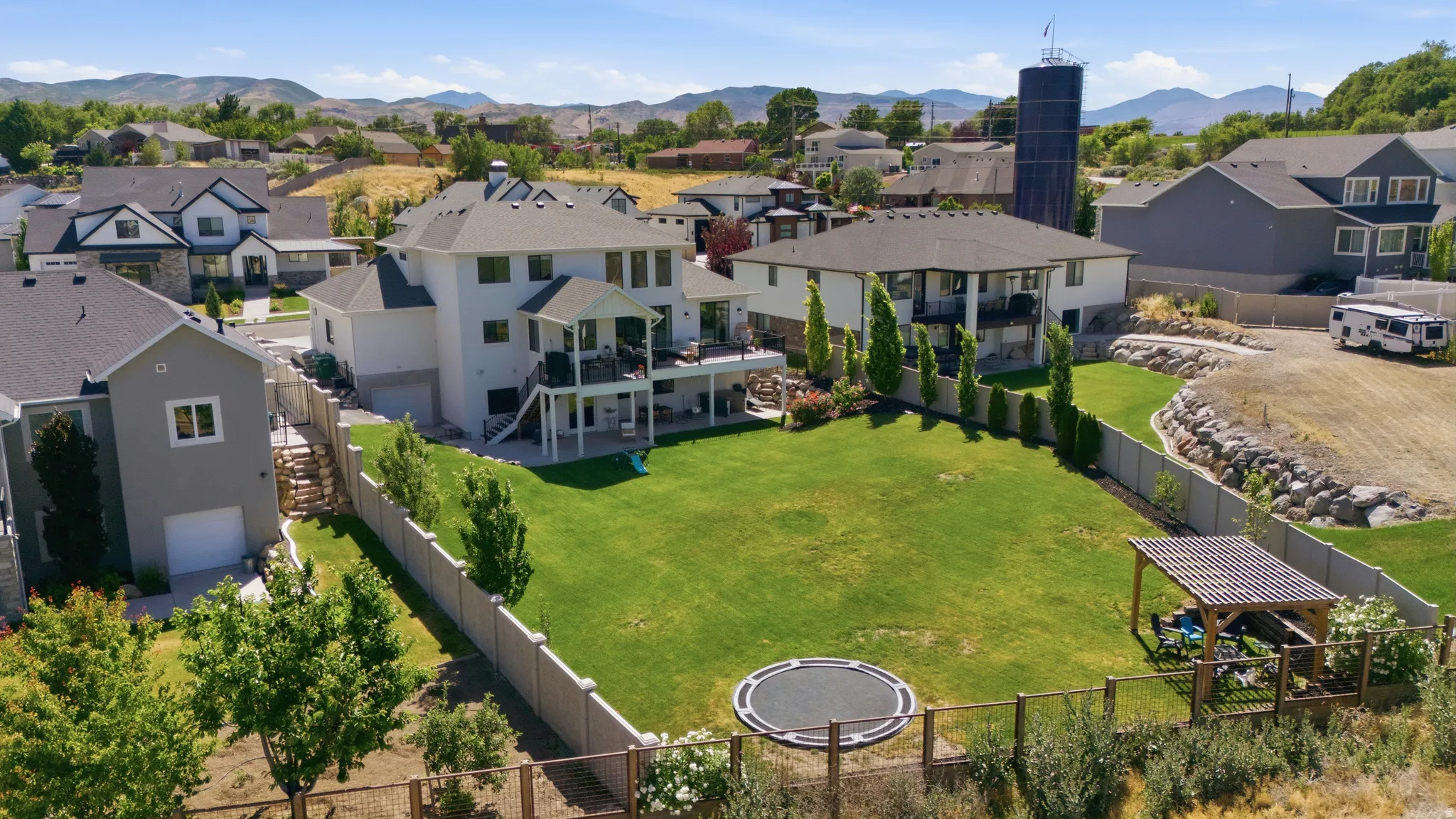 Expansive rear yard featuring a manicured lawn, established landscaping, and a fenced perimeter