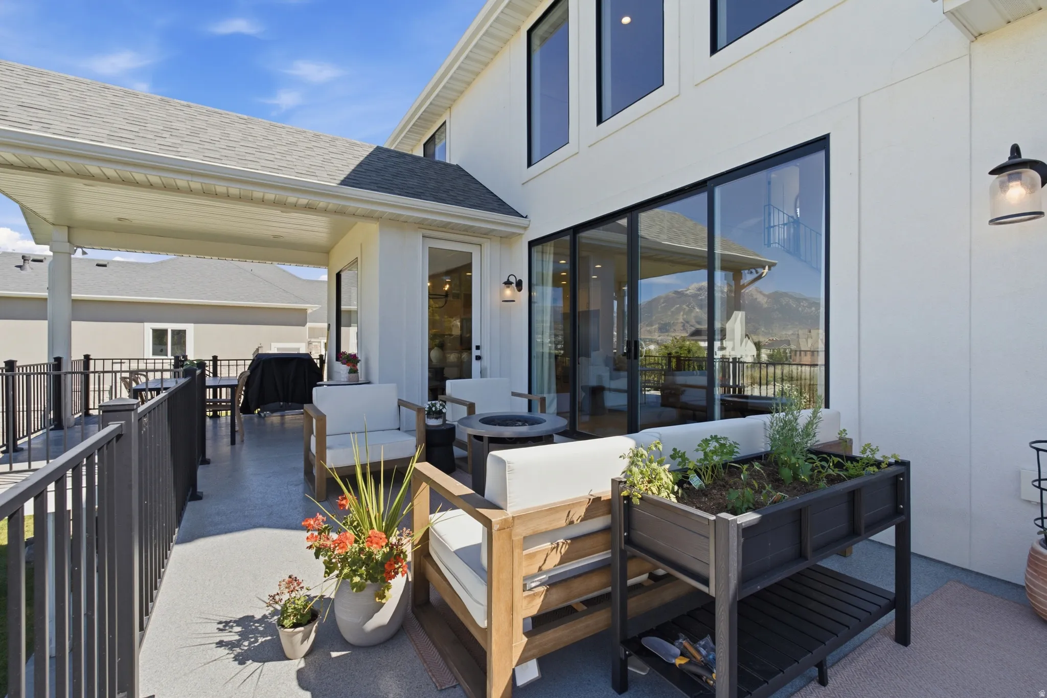 Expansive covered patio featuring a gray composite deck, black metal railings, and a white vinyl soffit