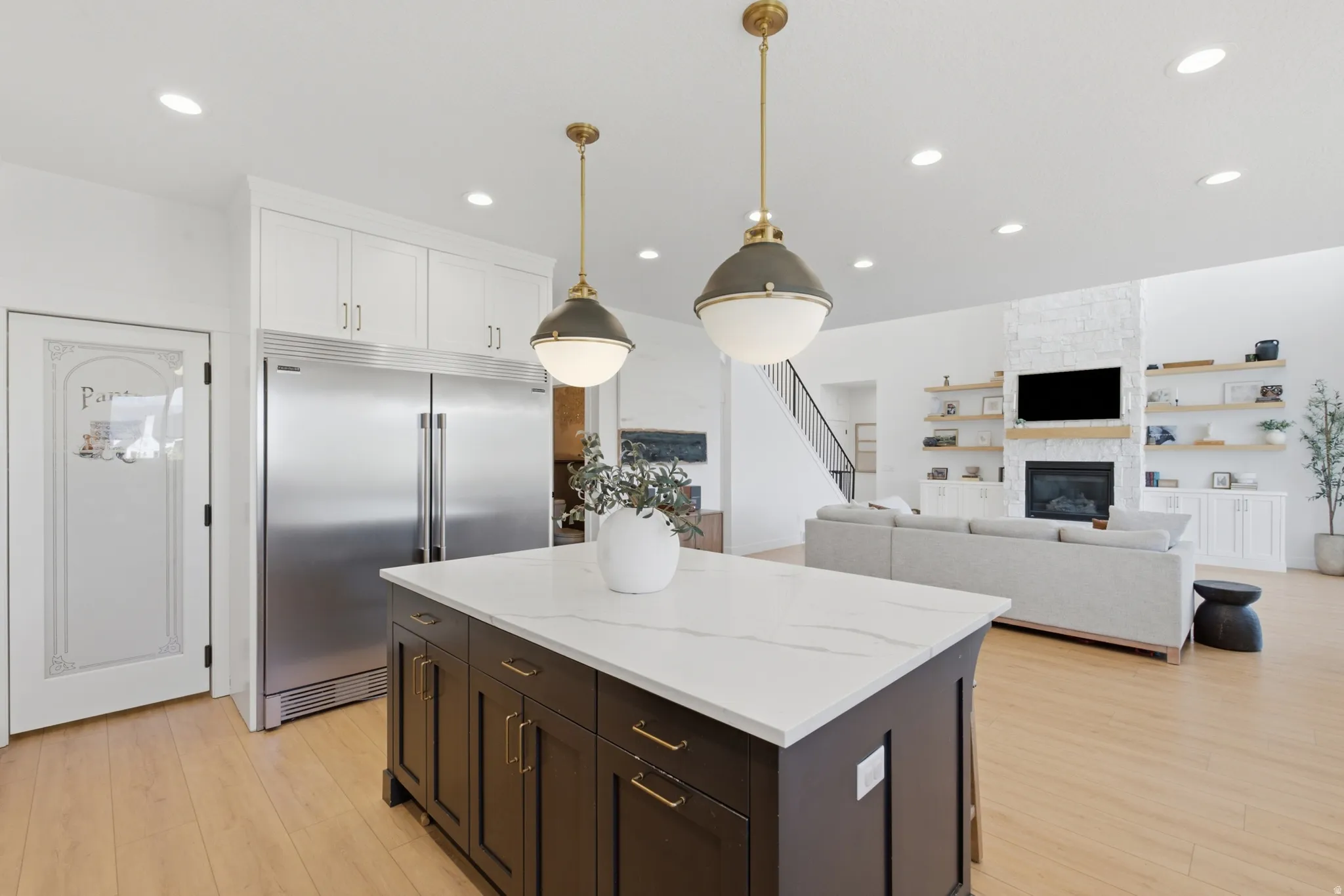 Kitchen island with a white countertop and dark cabinetry, illuminated by pendant lighting