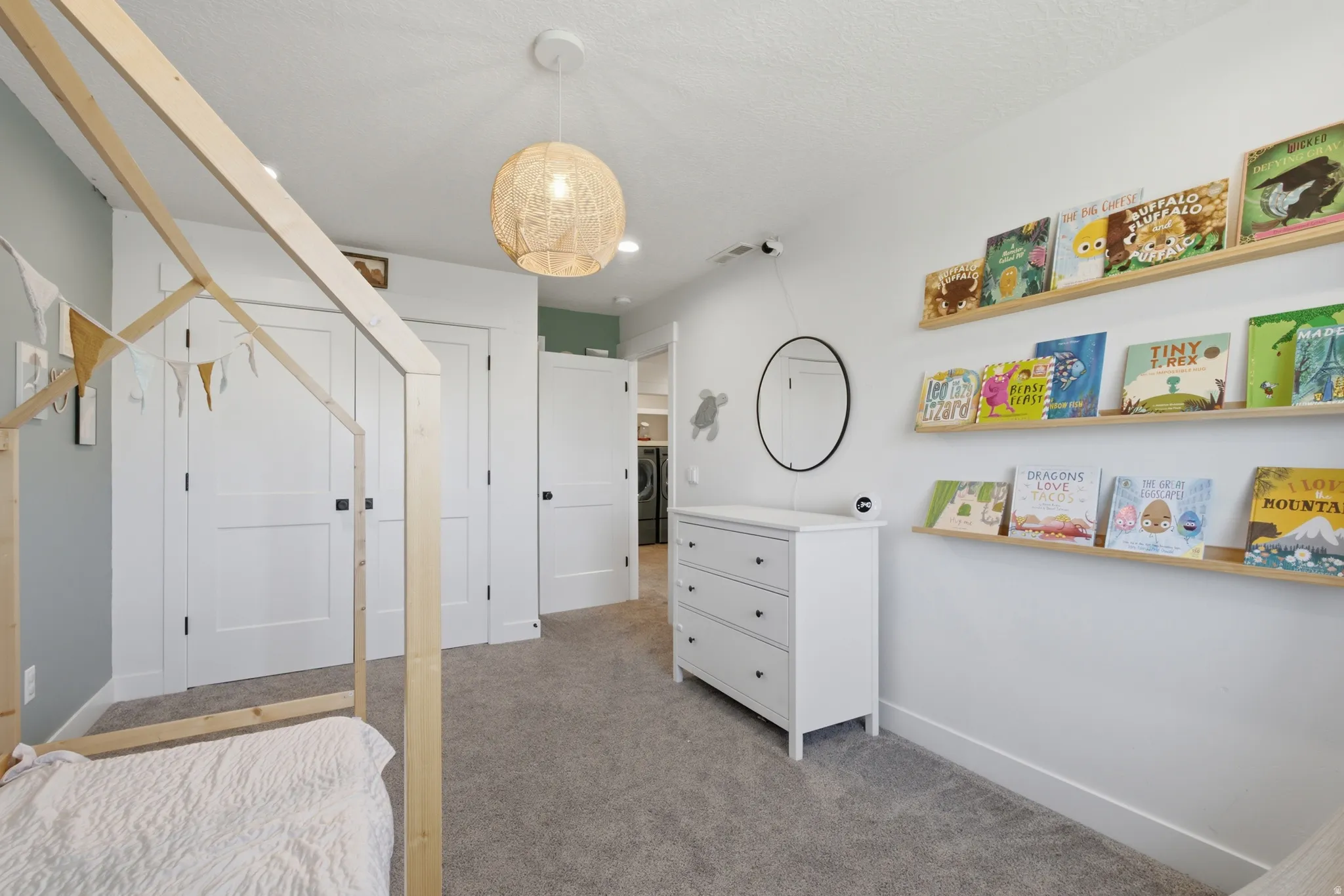 Interior room featuring light gray carpeting, white walls, and a modern woven pendant light fixture