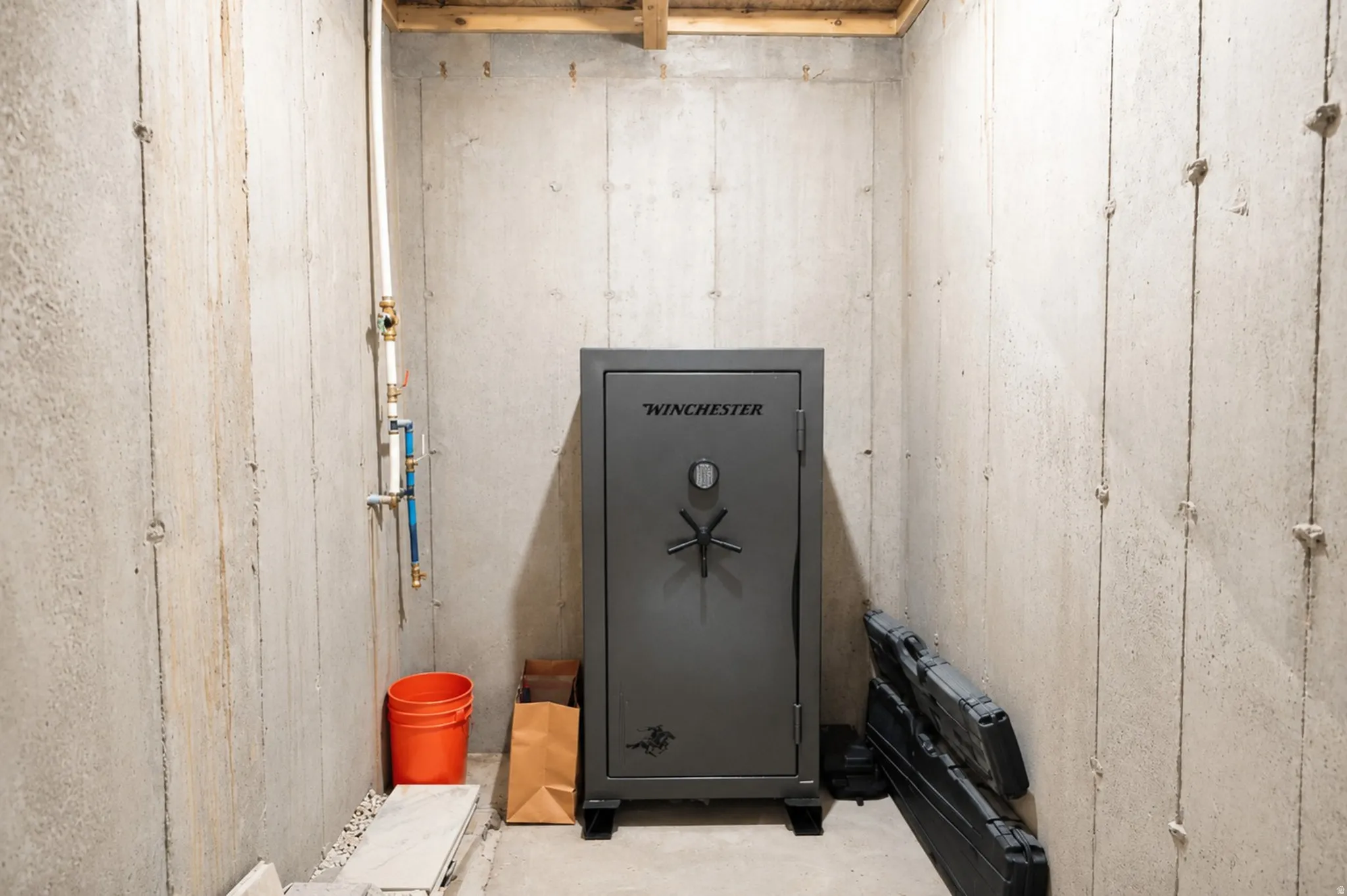 Unfinished basement space featuring exposed concrete walls and ceiling joists