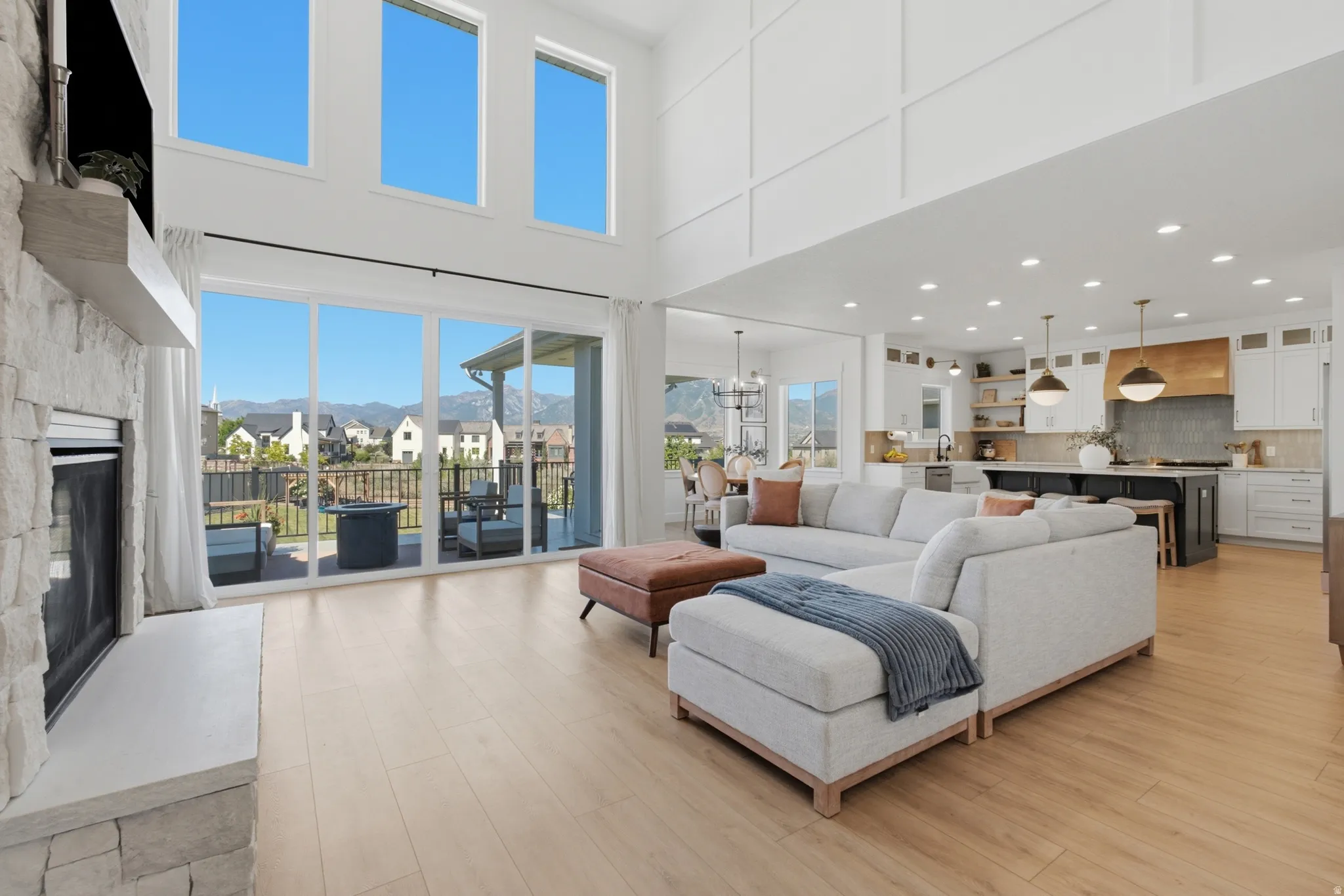 Spacious living area featuring high ceilings, wood-finish flooring, and a stone-faced fireplace