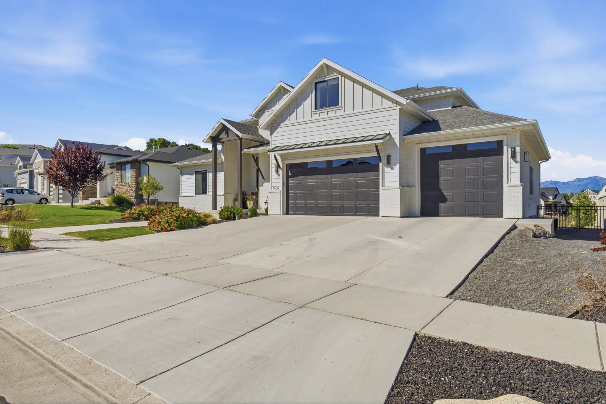 Contemporary multi-level residence featuring board and batten siding, a two-car garage with dark paneled doors, and a concrete driveway