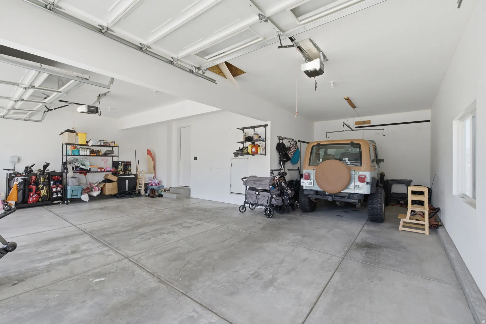 Spacious three-car garage featuring concrete flooring, multiple garage door openers, and ample wall space