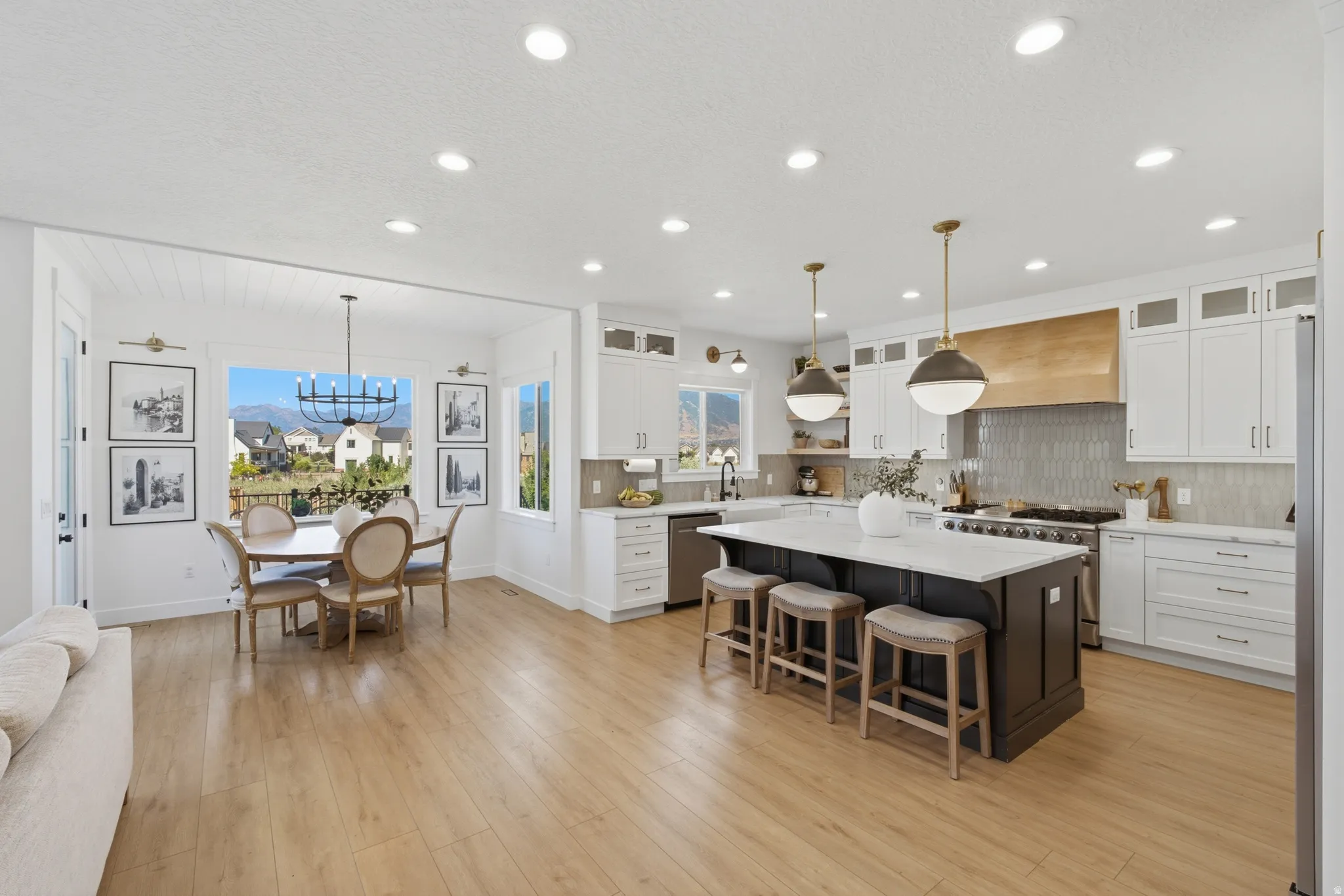 Open-concept living space featuring wood-finish flooring, recessed lighting, and a dining area with a mountain backdrop