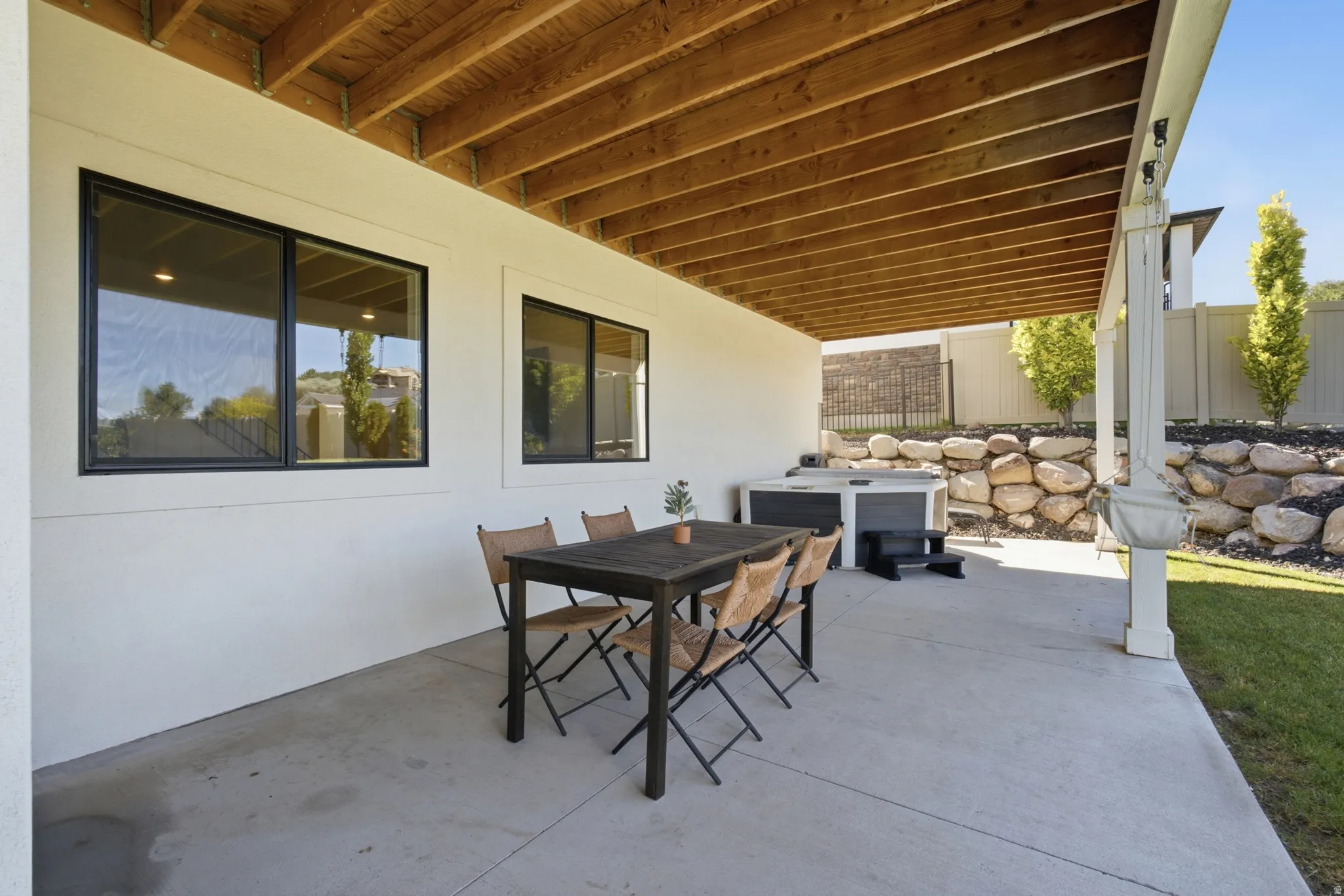 Covered concrete patio featuring an exposed wood ceiling, white columns, and perimeter lighting