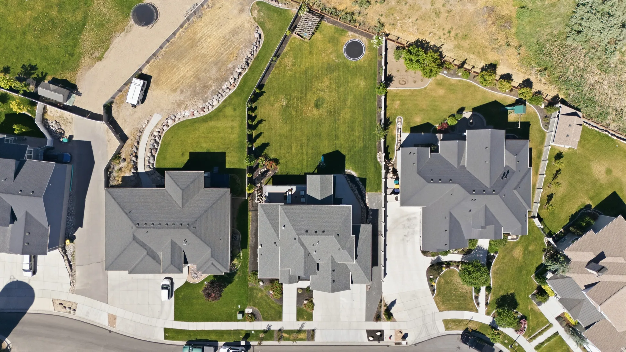 Aerial perspective showcasing a property with a spacious backyard, manicured lawn, and mature perimeter landscaping