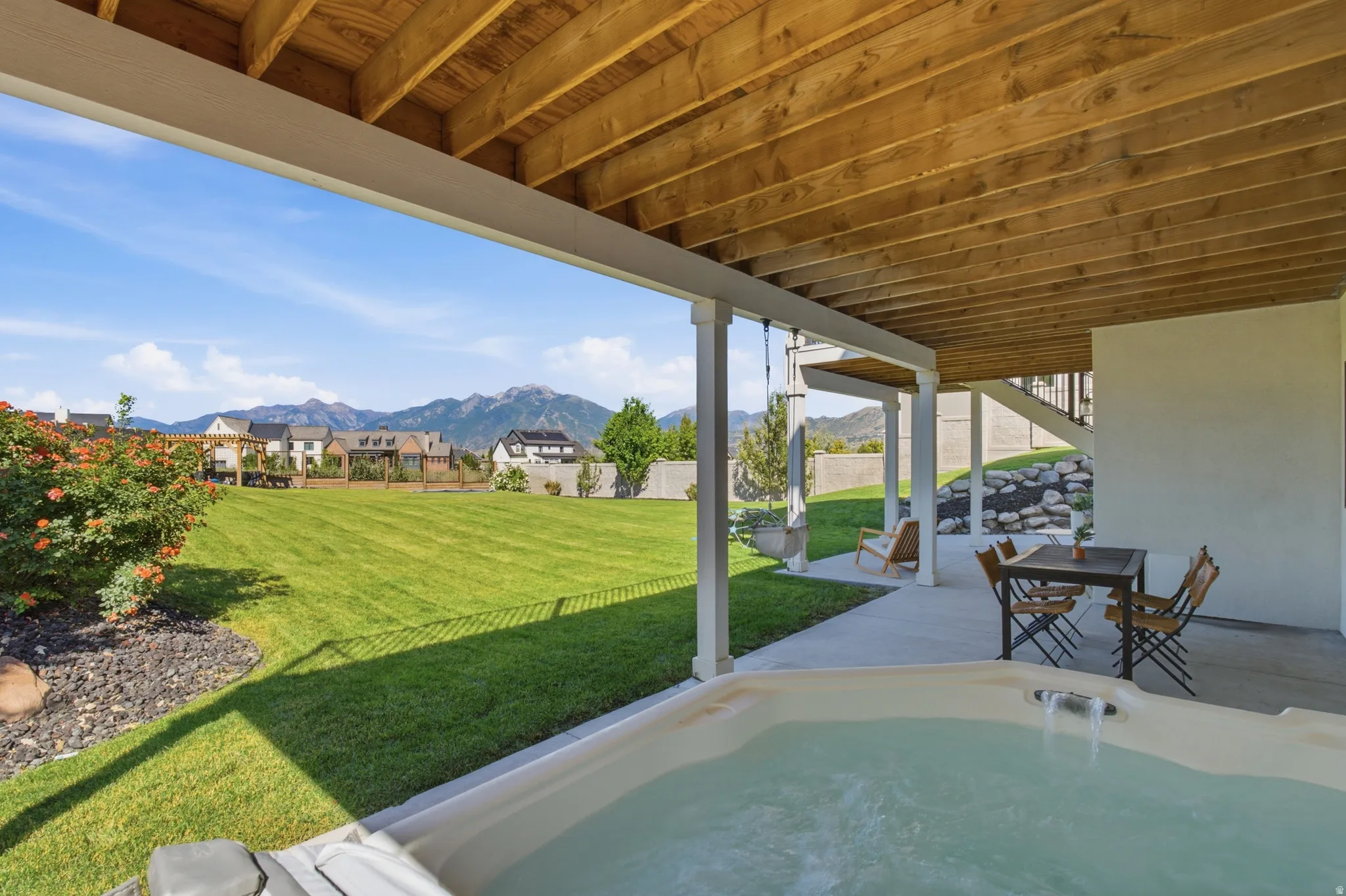 Patio area with an integrated hot tub and an exposed wood-beam ceiling