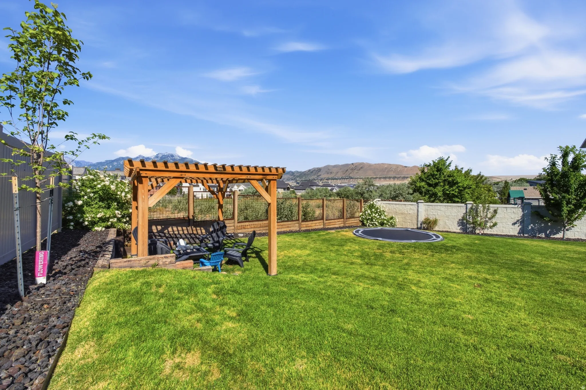 Expansive green lawn featuring a wooden pergola, privacy fencing, and a mountain backdrop