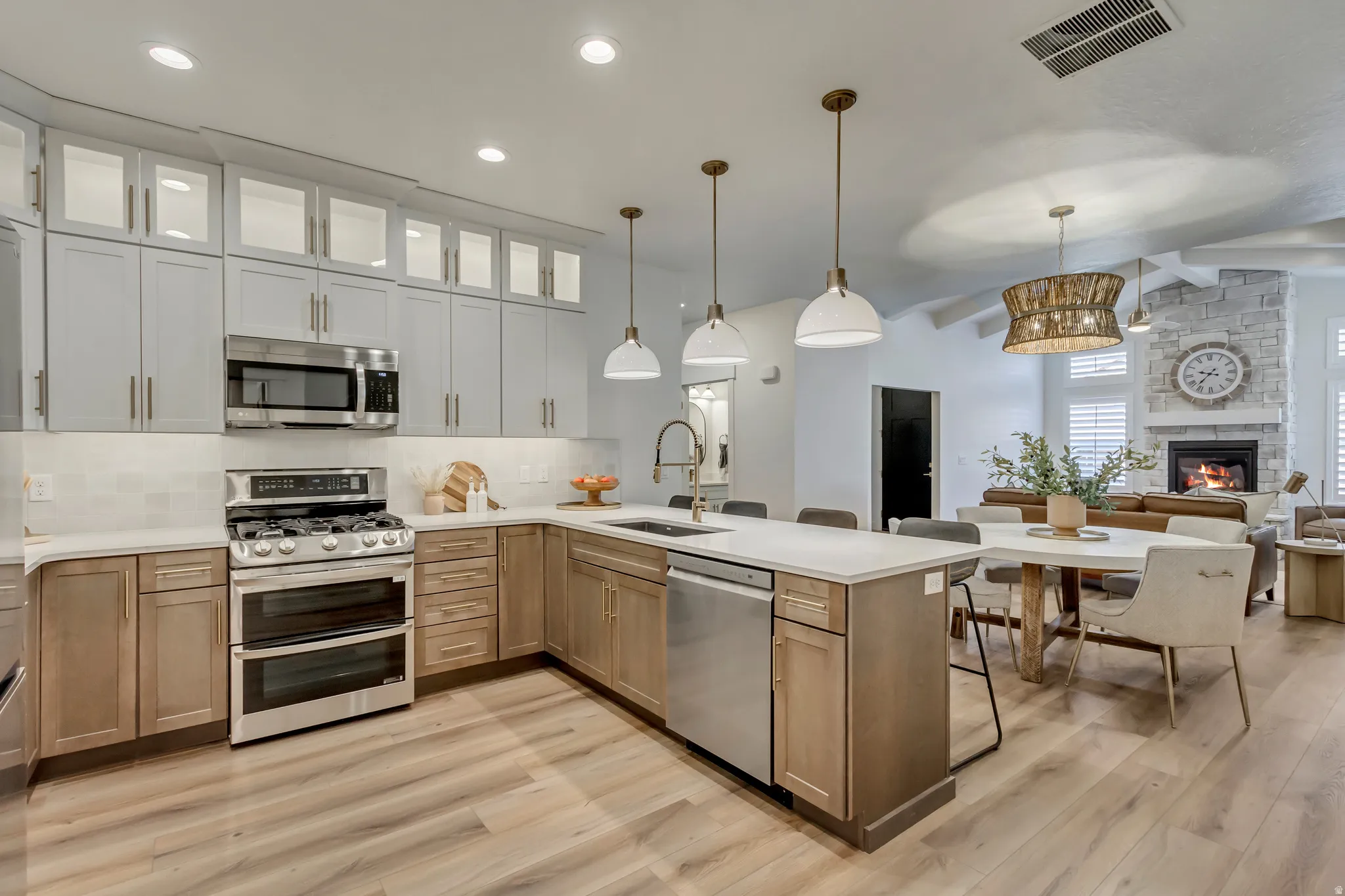 Open-concept kitchen featuring two-tone cabinetry, stainless steel appliances, and a central island with countertop seating