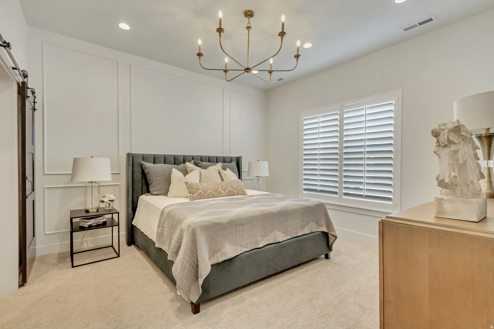 Bedroom featuring white wall paneling, a contemporary chandelier, recessed lighting, and a barn door entry